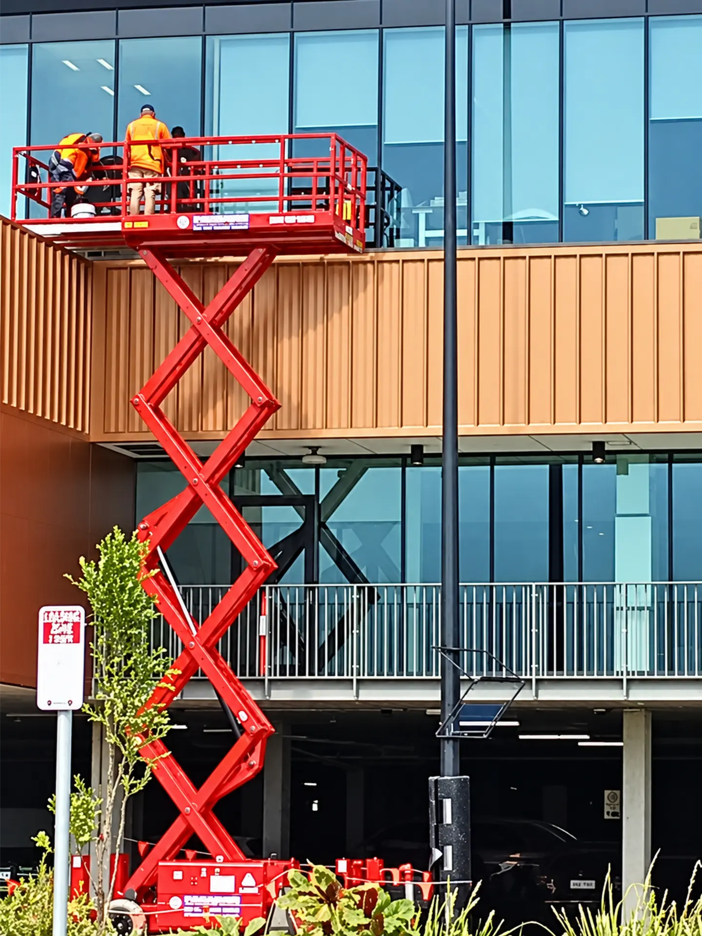 Glaziers working from a scissor lift beside upper-storey commercial windows