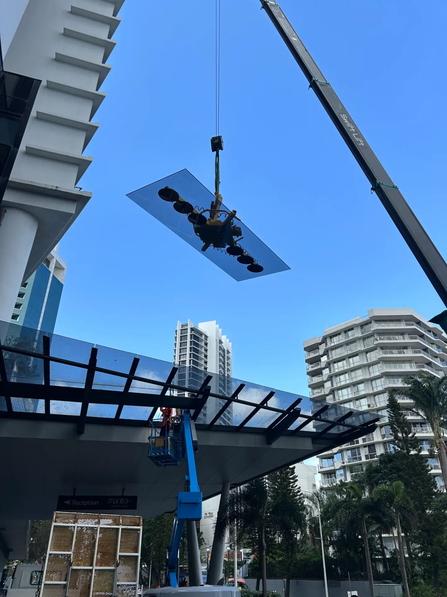 Large glass pane lifted by a crane with suction equipment at a Gold Coast commercial building