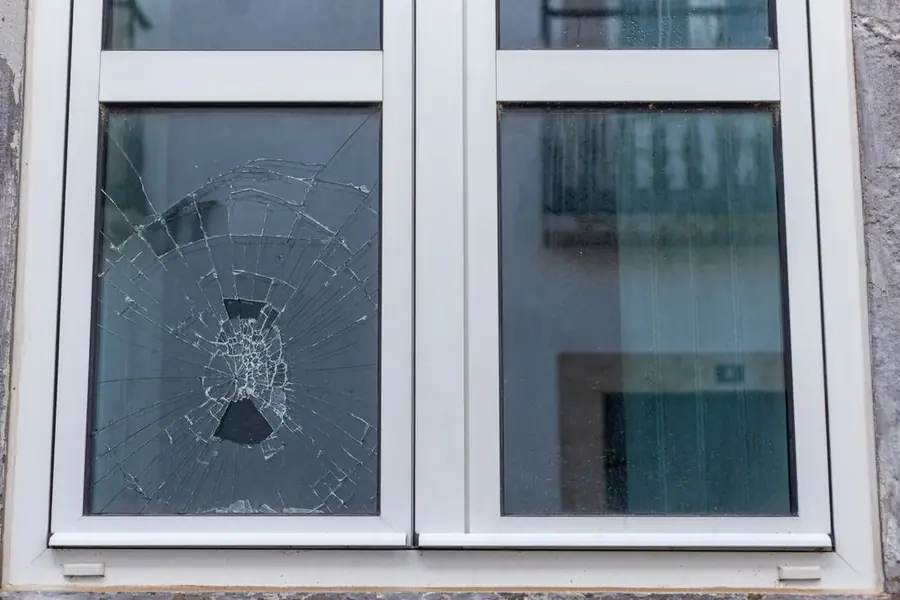 Close-up of a cracked window pane with a balcony visible beyond