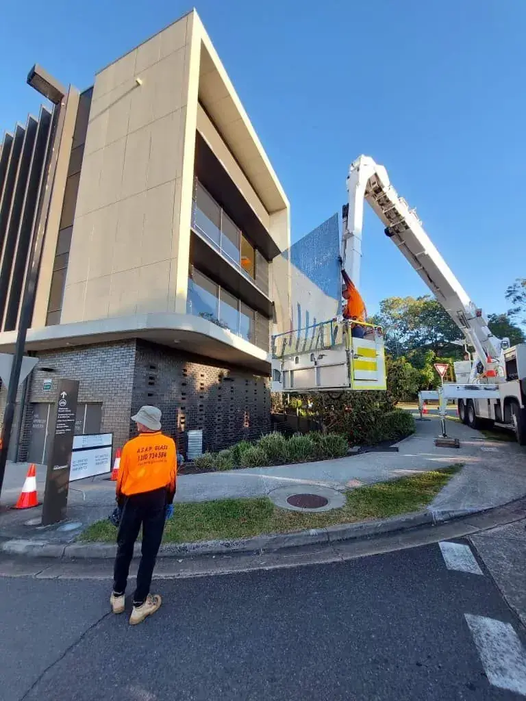 ASAP Glass technician in branded orange workwear on site at a commercial glass job