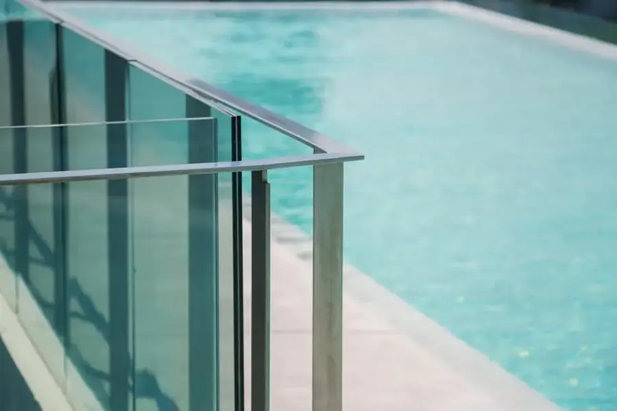 Close-up of a frameless glass balustrade beside a swimming pool